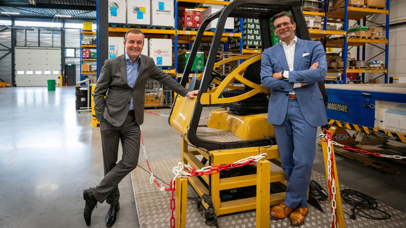 Sjoerd Boot en Johan Kerver, in een magazijn leunend op een cabine van een machine.
